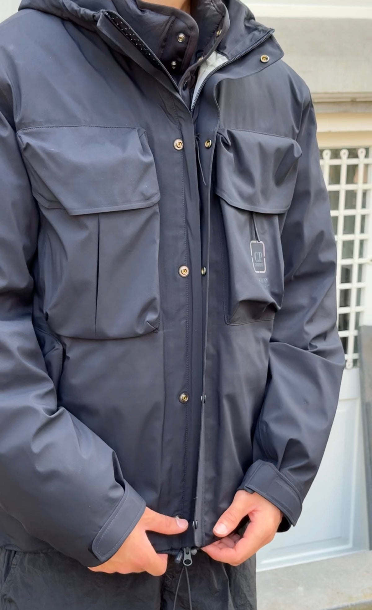 Model with black wind jacket and hand on buttons