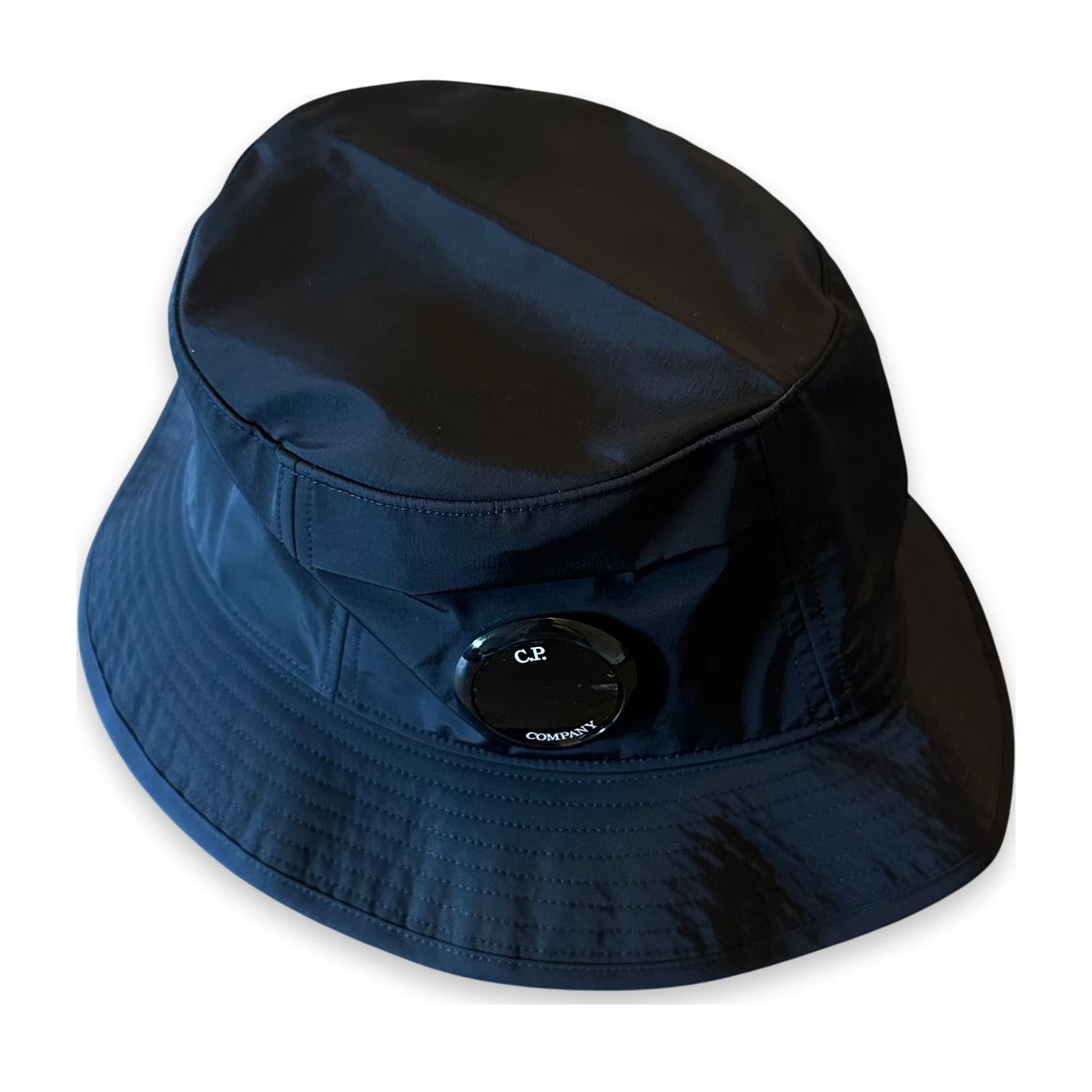 A dark navy blue bucket hat with a black circular ventilation valve on the side, shown against a plain white background.