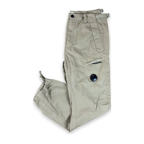 A pair of light khaki cargo pants with adjustable cuffs and dark button details, laid flat on a white background.