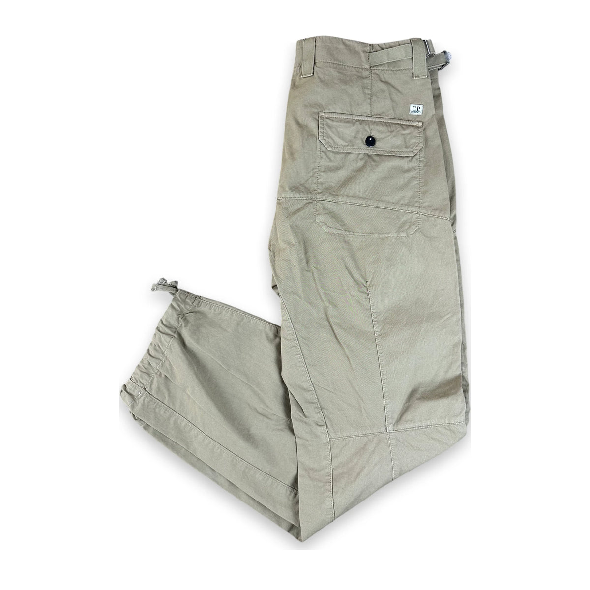 A pair of light khaki cargo pants laid flat on a white background, featuring a buttoned cargo pocket and elasticized ankle cuffs.