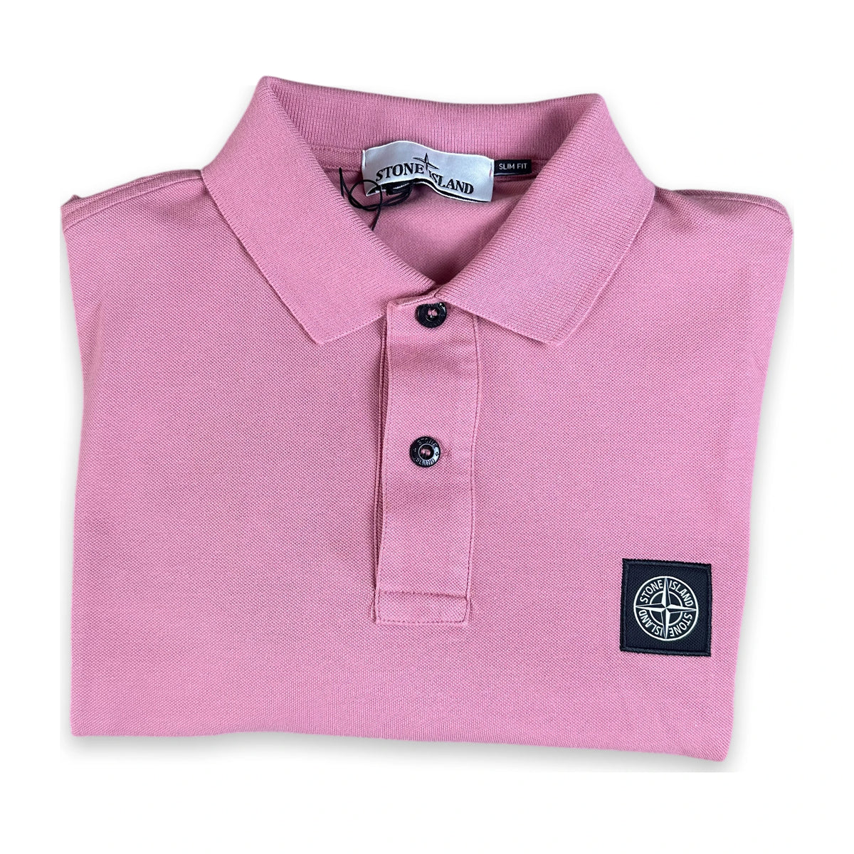 A folded pink Stone Island polo shirt with a black button placket and a black woven compass logo patch on the left chest, shown on a white background.