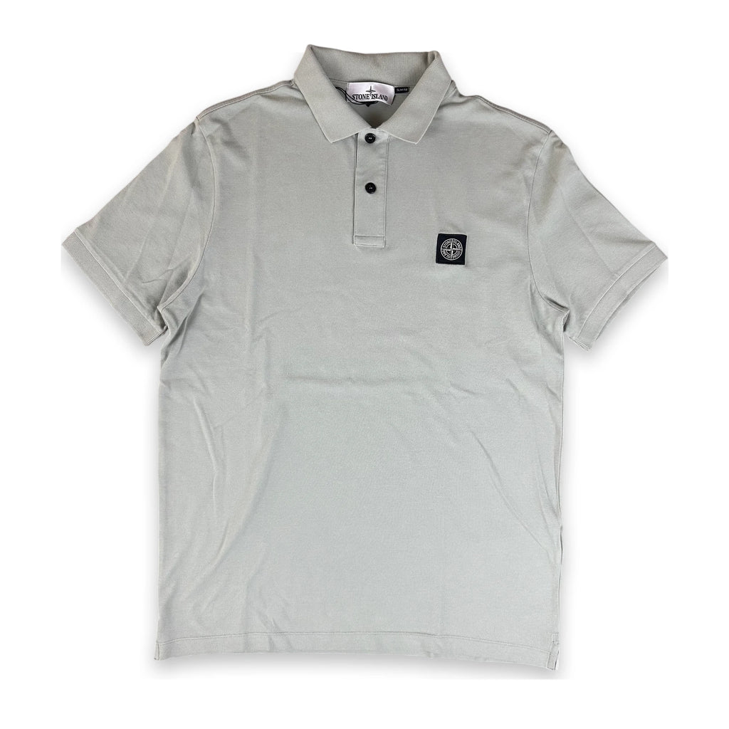 A light gray short-sleeve polo shirt with a two-button placket and a small black square logo patch on the left chest, displayed flat against a white background.