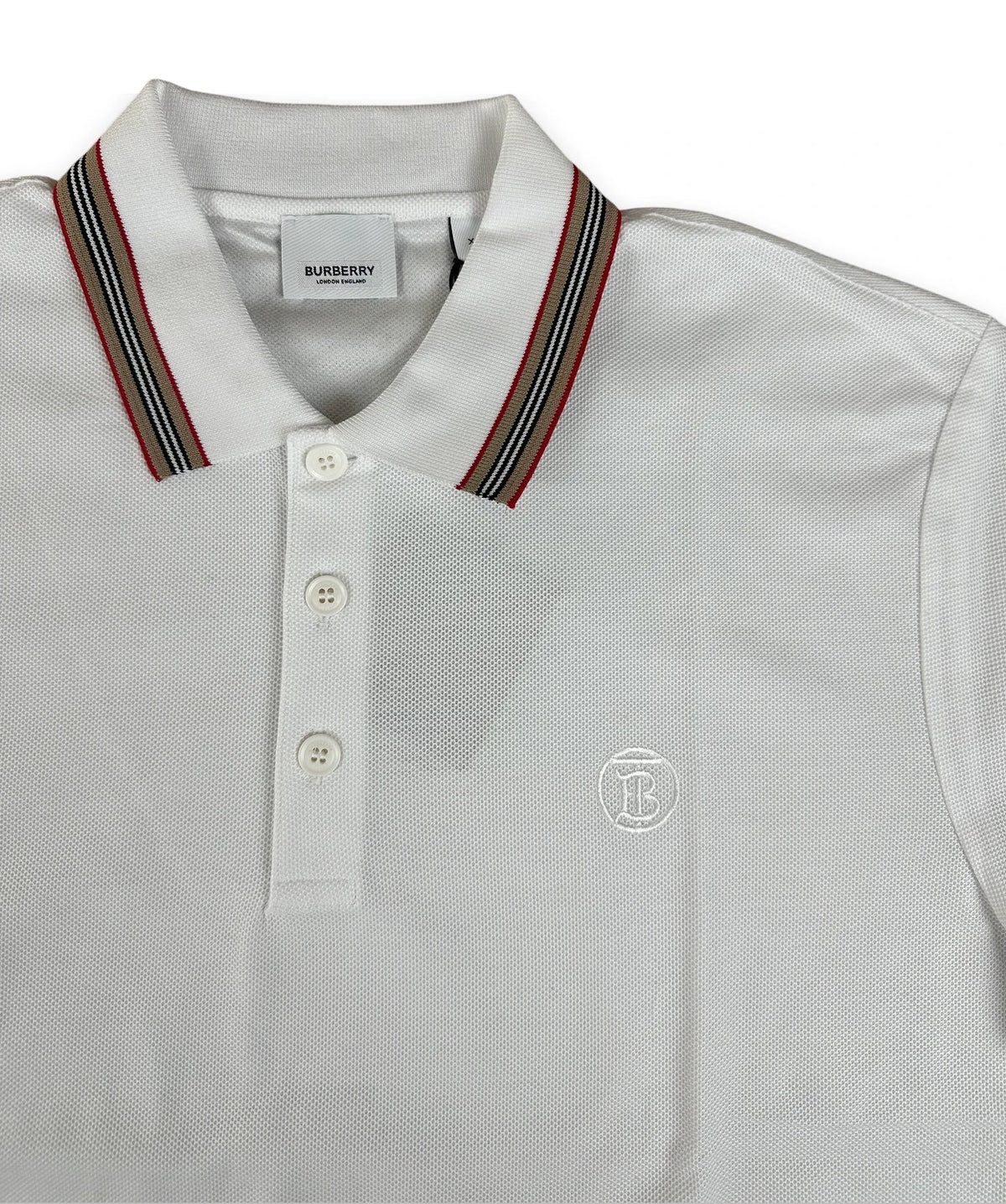 A white Burberry polo shirt with a striped navy, red, and gold collar, featuring a three-button placket and a small embroidered crest on the chest.