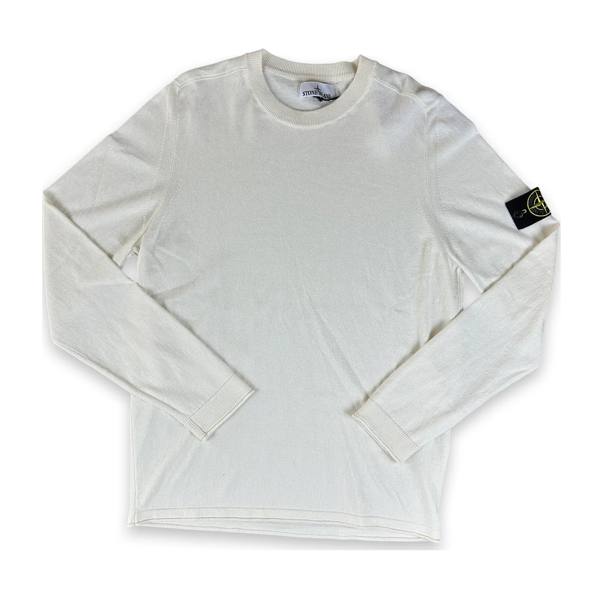 An off-white long-sleeve crewneck shirt by Stone Island, featuring the brand's signature compass badge on the left sleeve, laid flat against a white background.