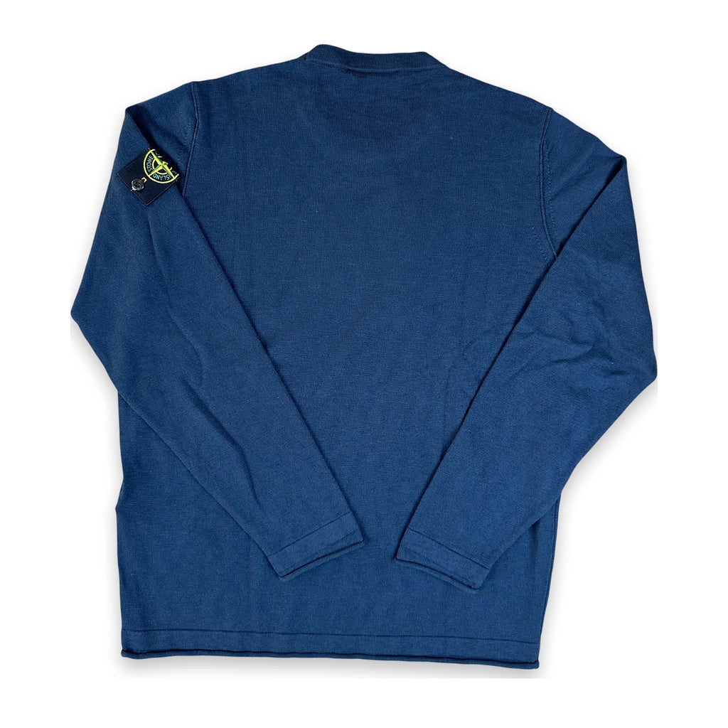 A dark blue long-sleeve shirt shown from the back, featuring the iconic Stone Island compass patch on the left shoulder, laid flat on a white background.