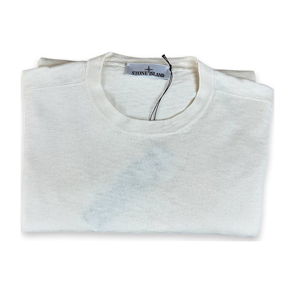 A folded Stone Island crewneck sweater in off-white cotton, shown on a clean white background with its brand tag visible inside the collar.