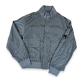 A gray nylon bomber jacket with a stand-up collar, button-up front, and flap pockets, laid flat on a white background.