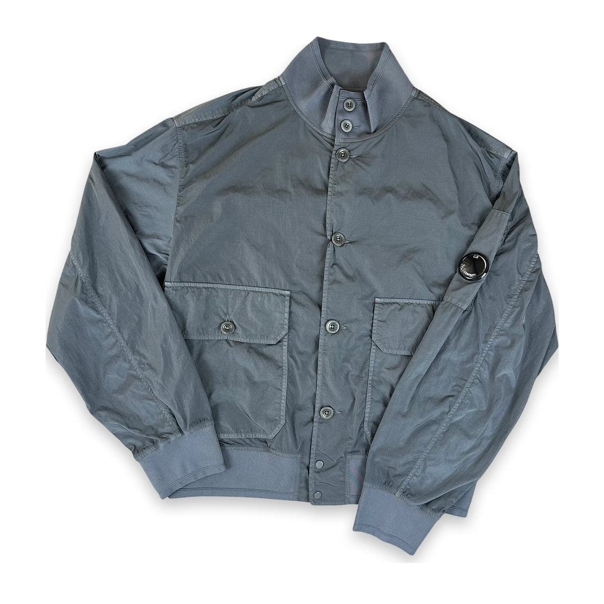 A gray nylon bomber jacket with a stand-up collar, button-up front, and flap pockets, laid flat on a white background.