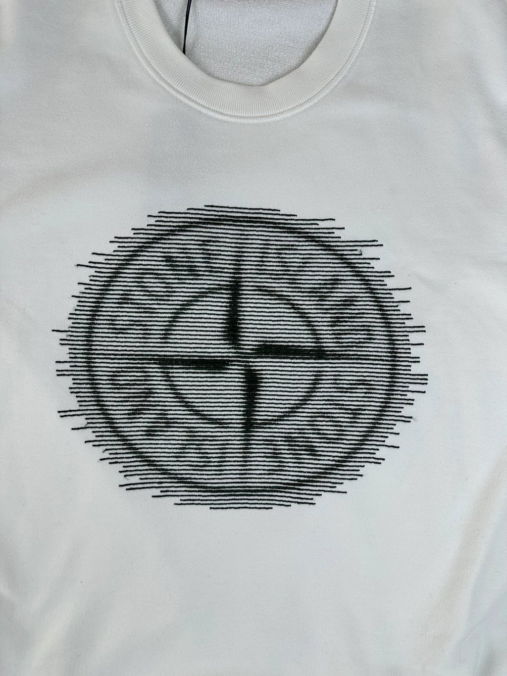 A white short-sleeve t-shirt featuring a black circular graphic on the chest with the text 'STONE ISLAND' and a compass-like symbol.