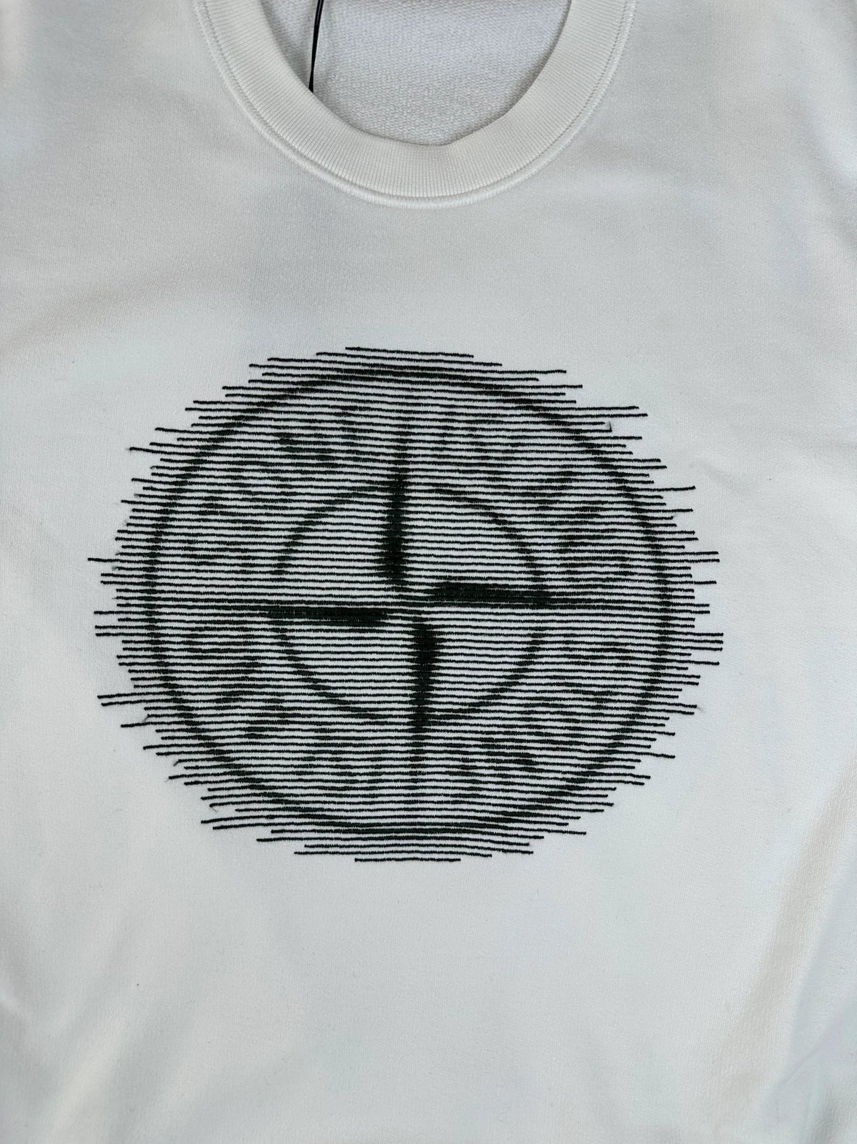 A white short-sleeve t-shirt featuring a black circular graphic on the chest with the text 'STONE ISLAND' and a compass-like symbol.