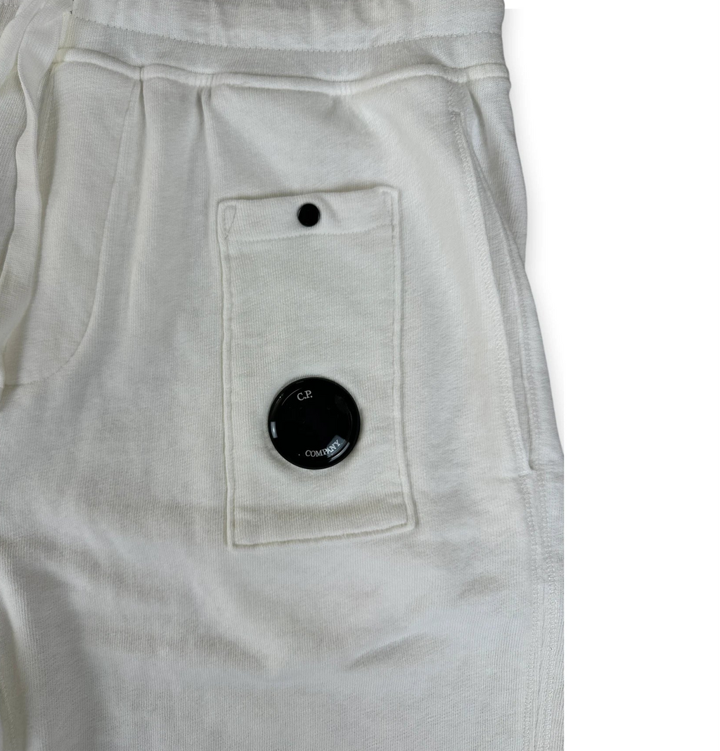 Close-up of off-white sweatpants showing a back pocket with a black snap button and a circular black dial detail.