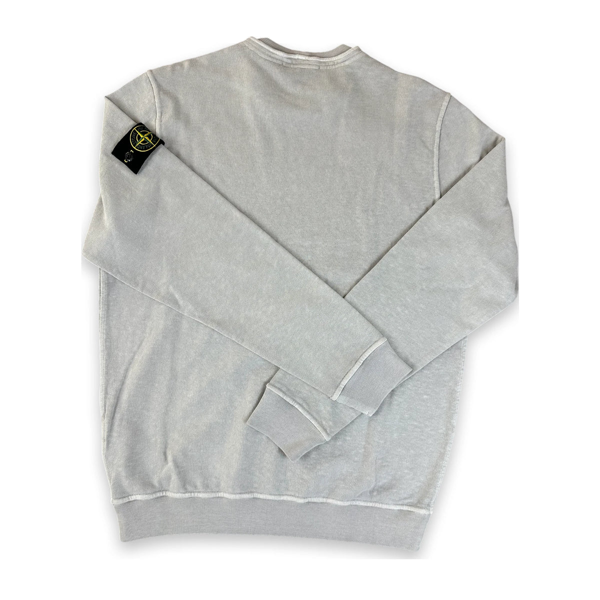 A light gray heather crewneck sweatshirt with the iconic Stone Island compass patch on the left sleeve, laid flat on a white background.