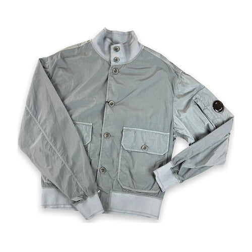 A light gray nylon utility jacket with a stand-up collar, button closure, and front flap pockets, laid flat on a white background.