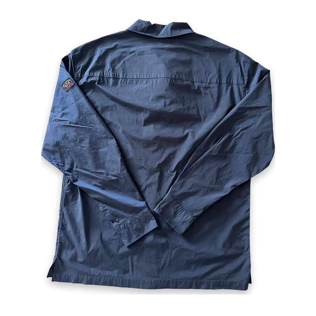 A dark navy blue long-sleeve shirt jacket shown from the back, laid flat on a white background. It features a collar, a vertical seam running down the center, and a small embroidered patch on the left shoulder.