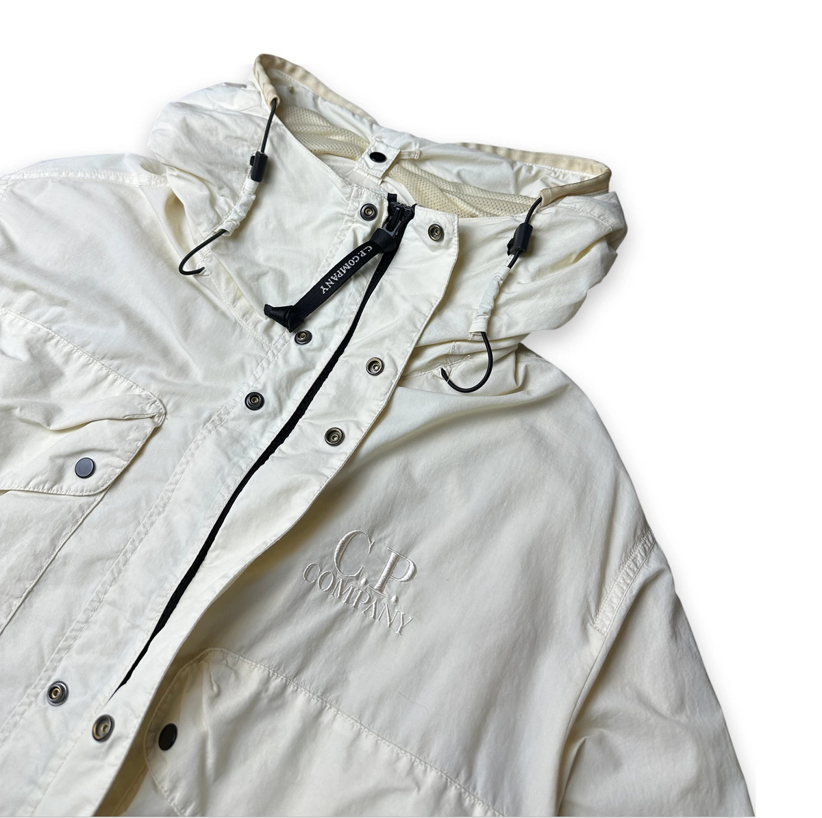 An off-white hooded utility jacket with black drawstrings and snap-button closure, featuring a tonal embroidered logo on the chest, shown on a plain white background.