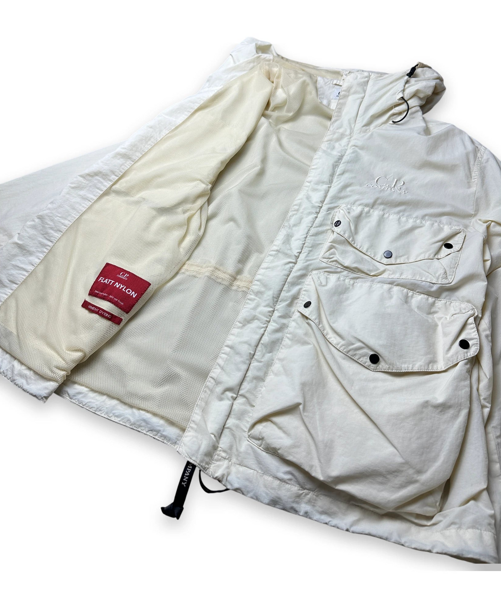 A cream-colored puffer jacket with a quilted design, multiple utility pockets, and a red 'FLATT NYLON' brand label on the inner lining, shown against a plain white background.