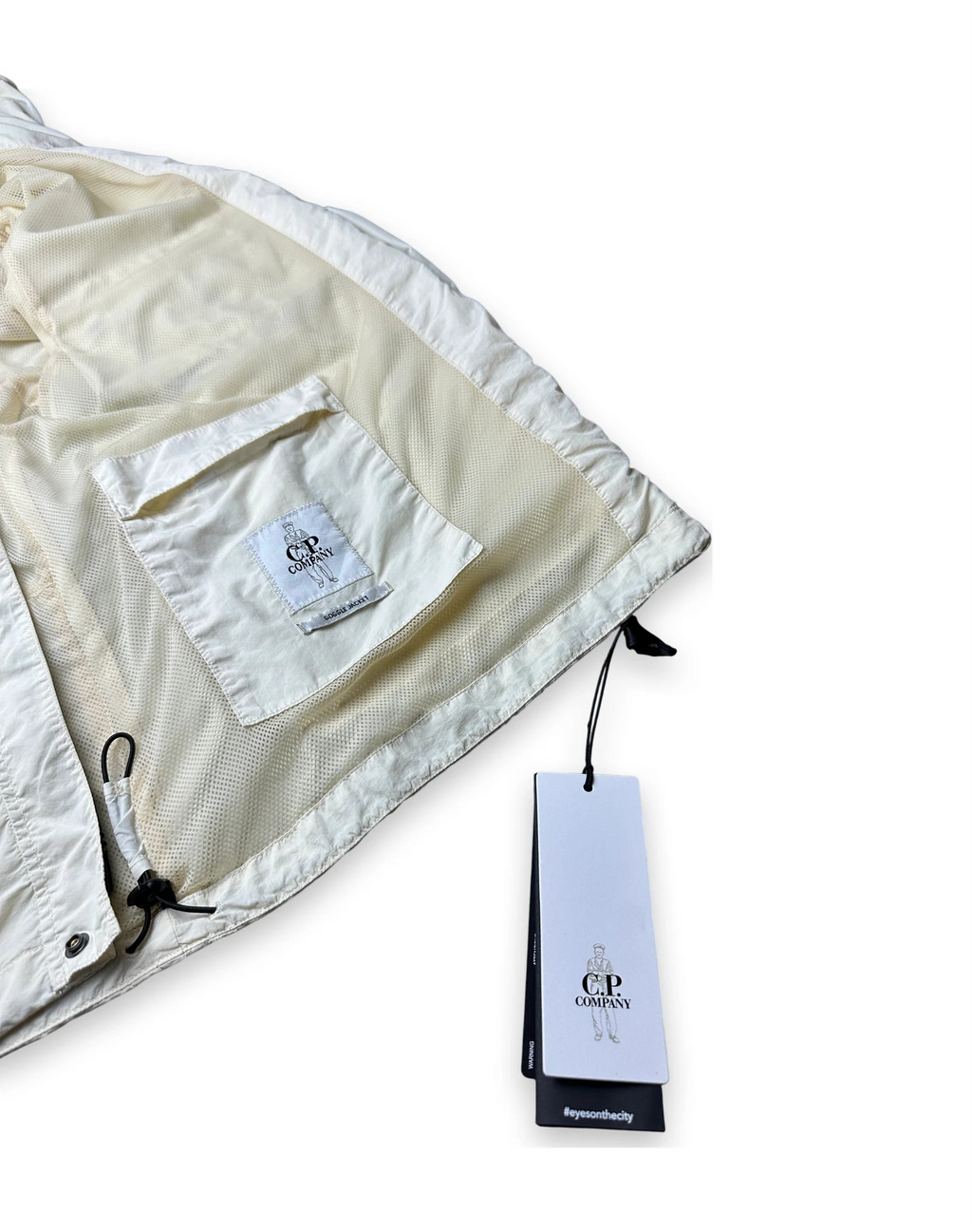 Inside of a cream jacket with the CP company label and a CP company swing tag