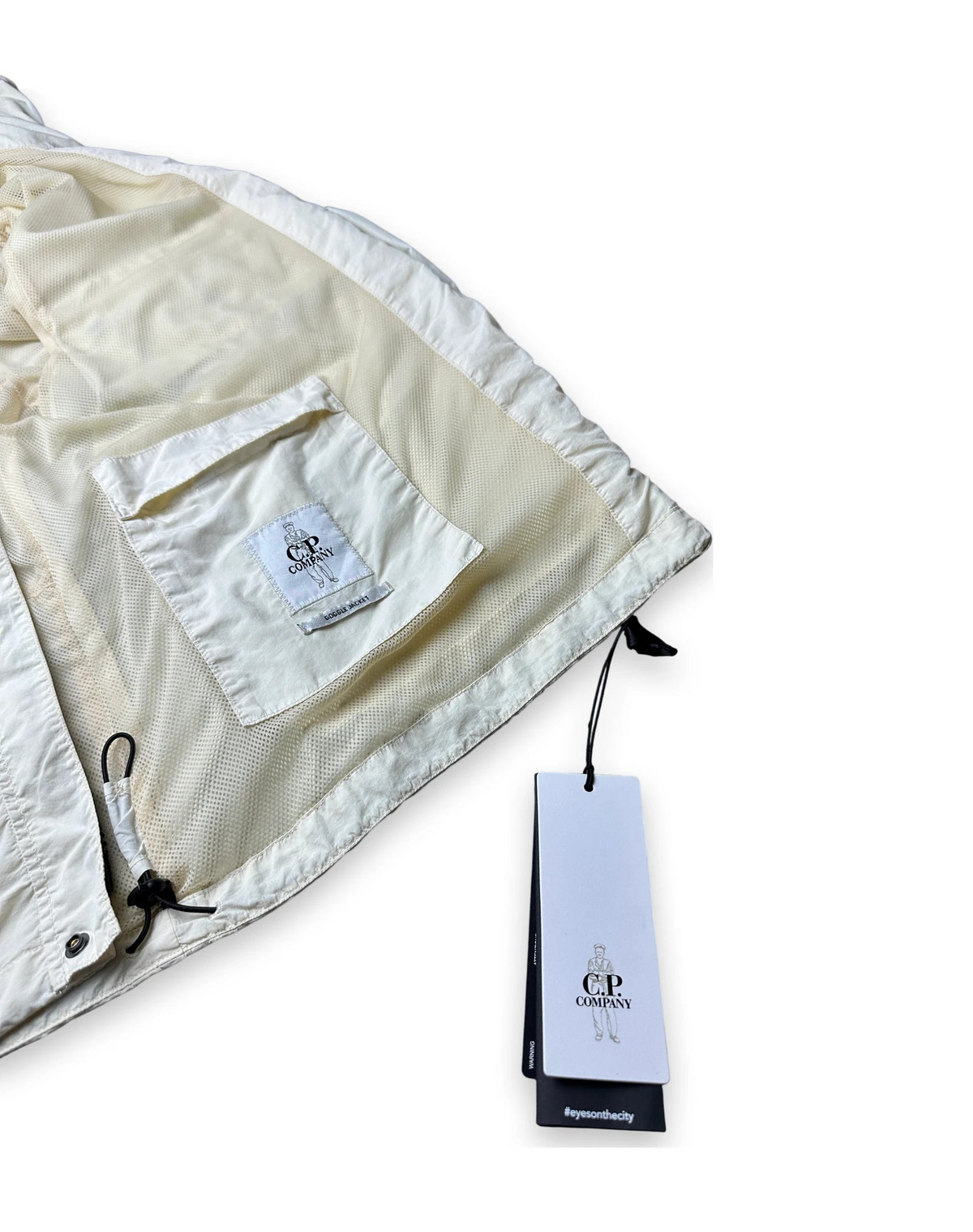 Inside of a cream jacket with the CP company label and a CP company swing tag