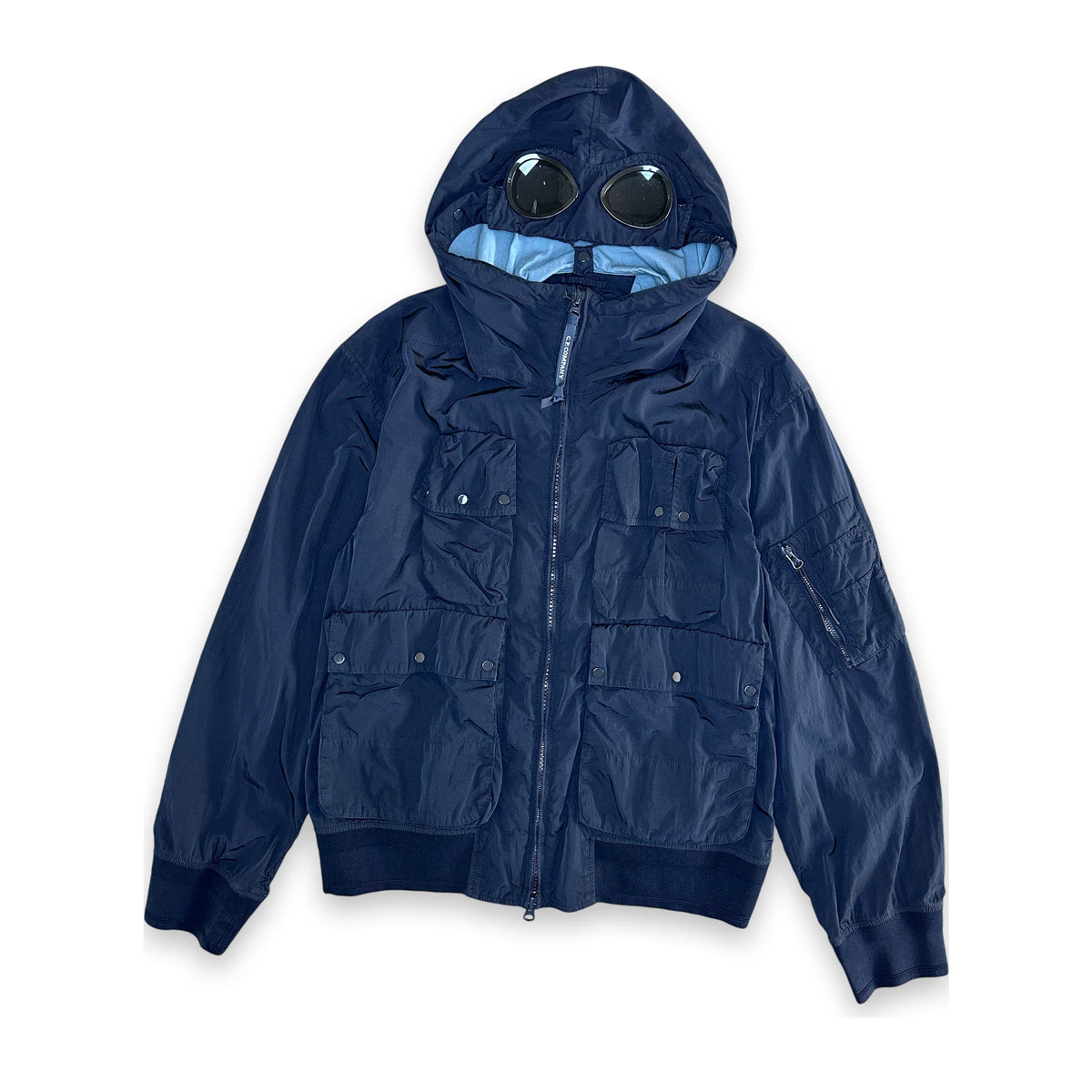 A navy blue hooded jacket with a unique integrated hood design featuring two circular black visor-like elements on the hood, photographed against a solid white background.