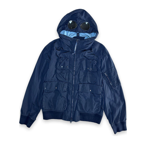 A navy blue hooded jacket with a unique integrated hood design featuring two circular black visor-like elements on the hood, photographed against a solid white background.