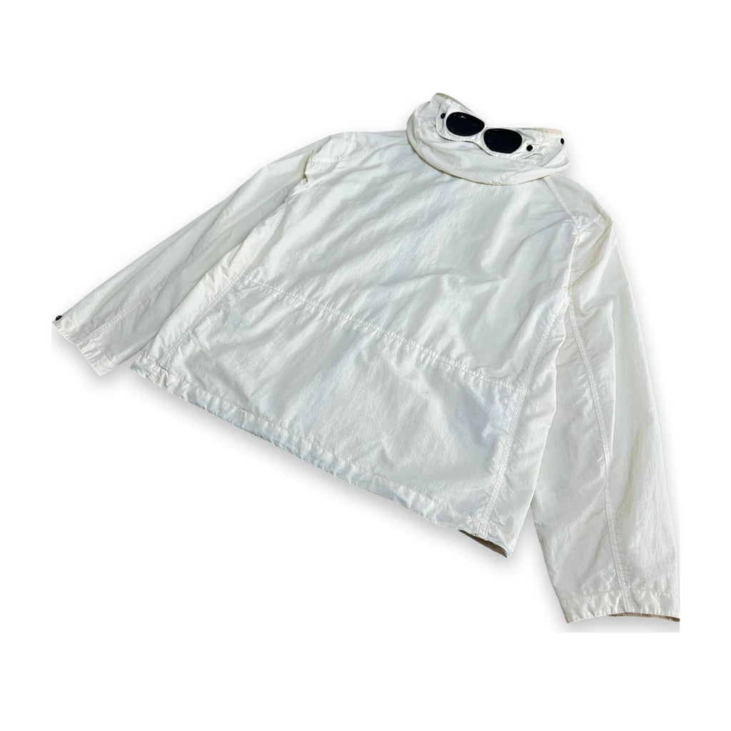A white lightweight jacket with a high collar, laid flat on a white background with a pair of black sunglasses resting on the collar.
