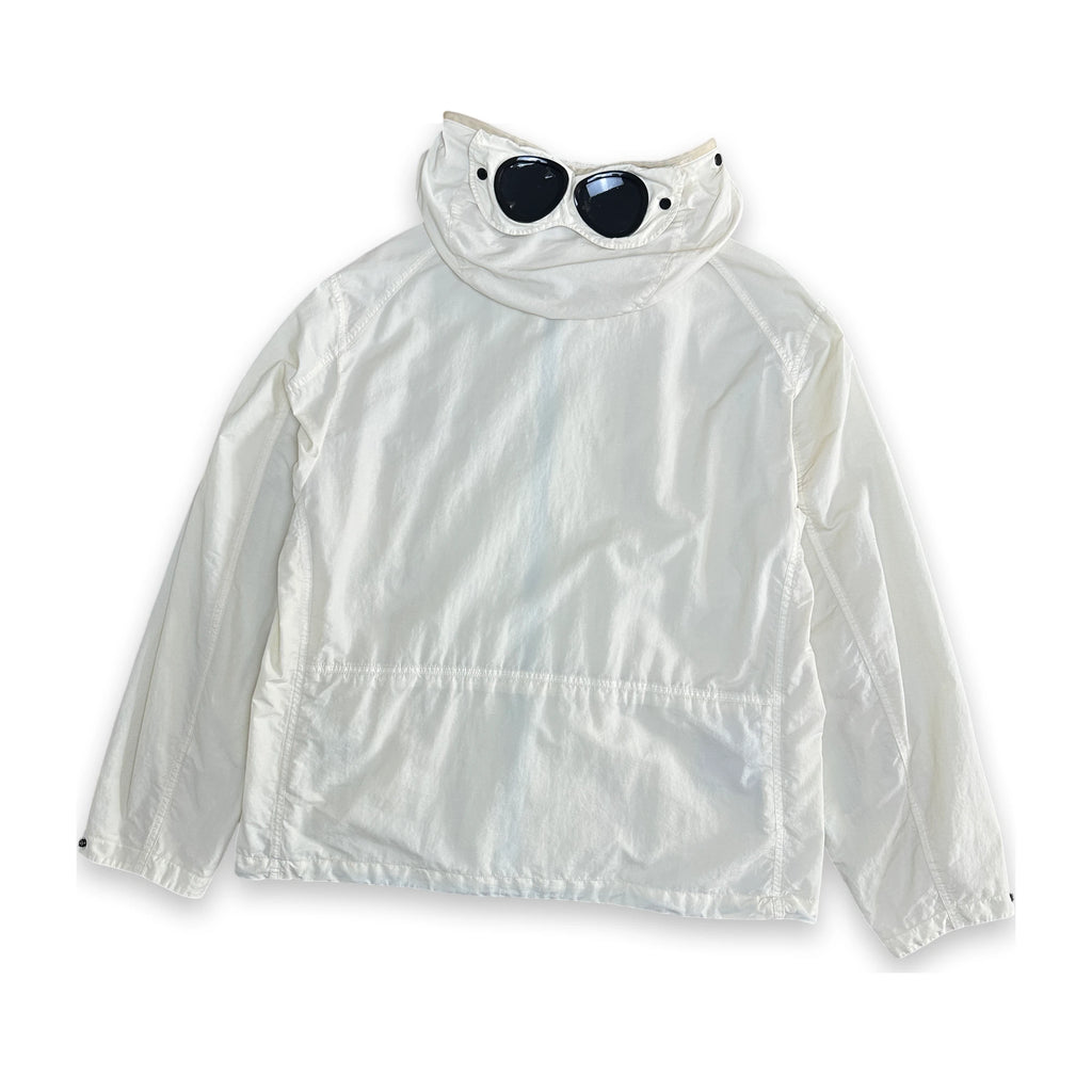 A white lightweight windbreaker jacket with a high collar, shown flat against a white background. Small black sunglasses are placed on top of the collar as a styling prop.