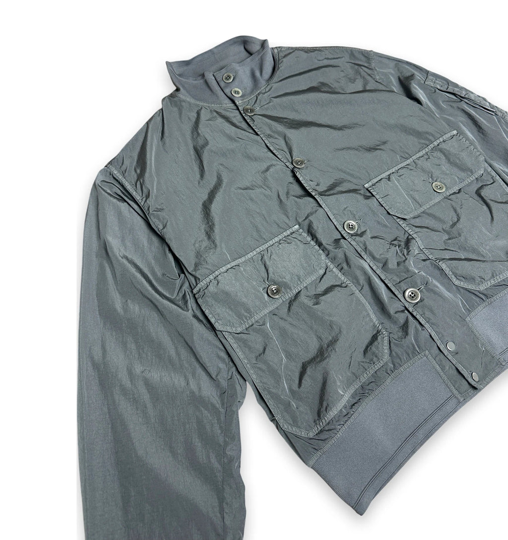 A gray lightweight jacket with a stand collar, button front, and two large front flap pockets, laid flat on a white background.