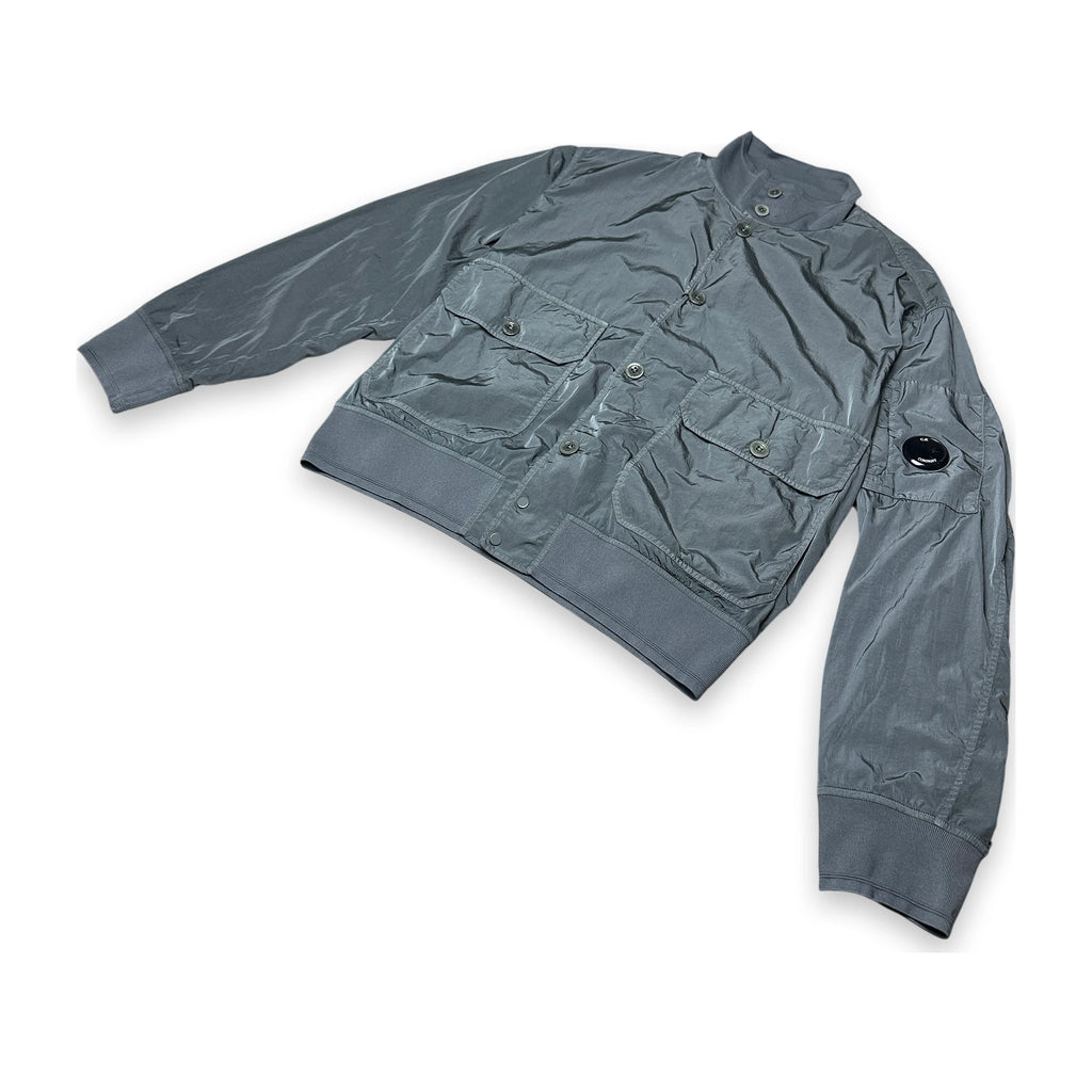 A gray utility jacket with multiple flap pockets and a stand-up collar, laid flat on a white background.