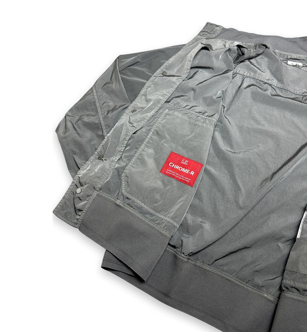 A gray waterproof jacket with a red 'Chrome R' brand patch on the pocket, shown folded on a white background.