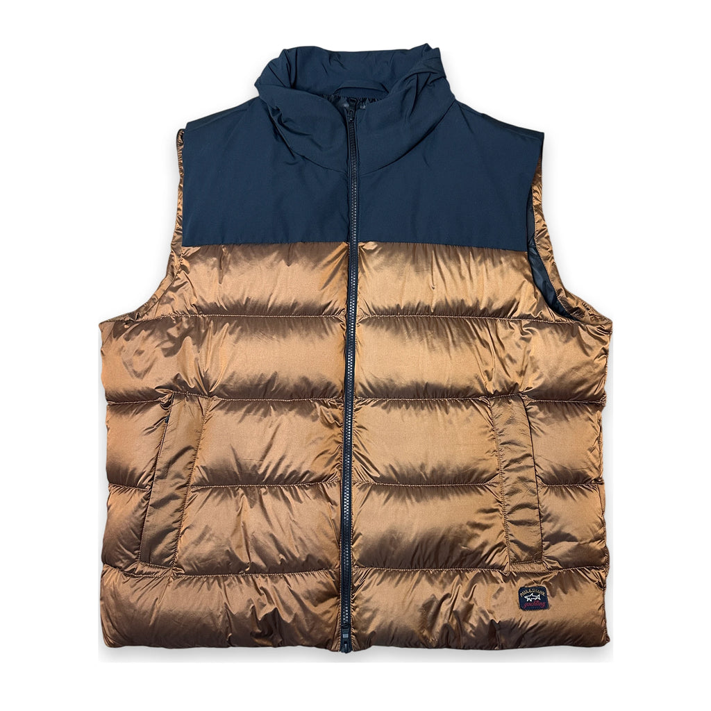 A color-blocked puffer vest with a navy blue upper section and a metallic bronze quilted lower section, featuring a full front zipper and a small brand patch near the bottom right.