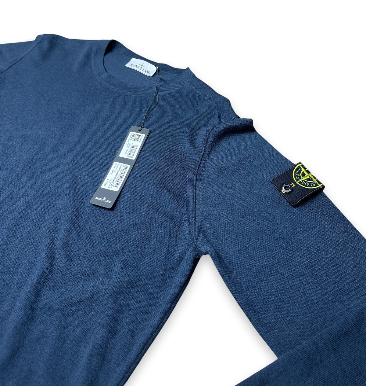 Navy jumper with on the sleeve a compass badge of Stone Island and the swing tag shown