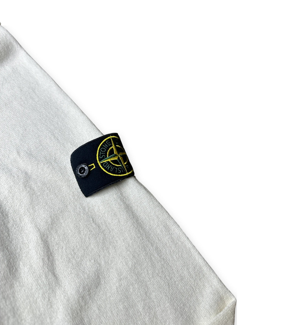 Close-up of a light heather gray fabric garment with a black Stone Island brand tag featuring a yellow compass logo.