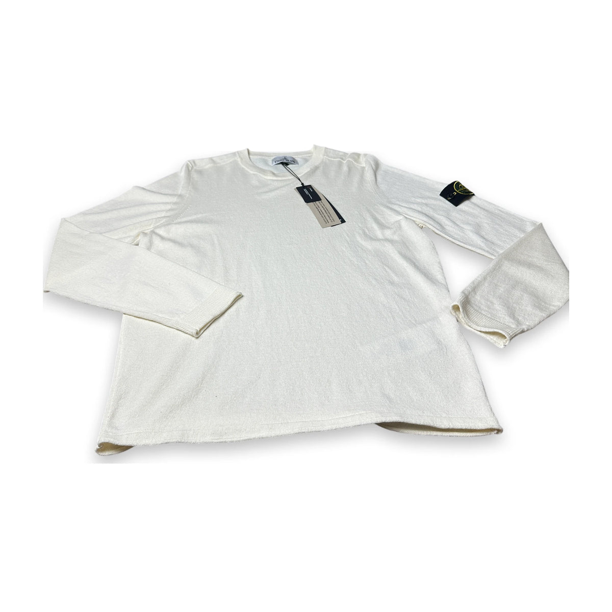 A white long-sleeve crewneck shirt with a Stone Island compass logo patch on the left sleeve, displayed flat against a white background with tags attached.