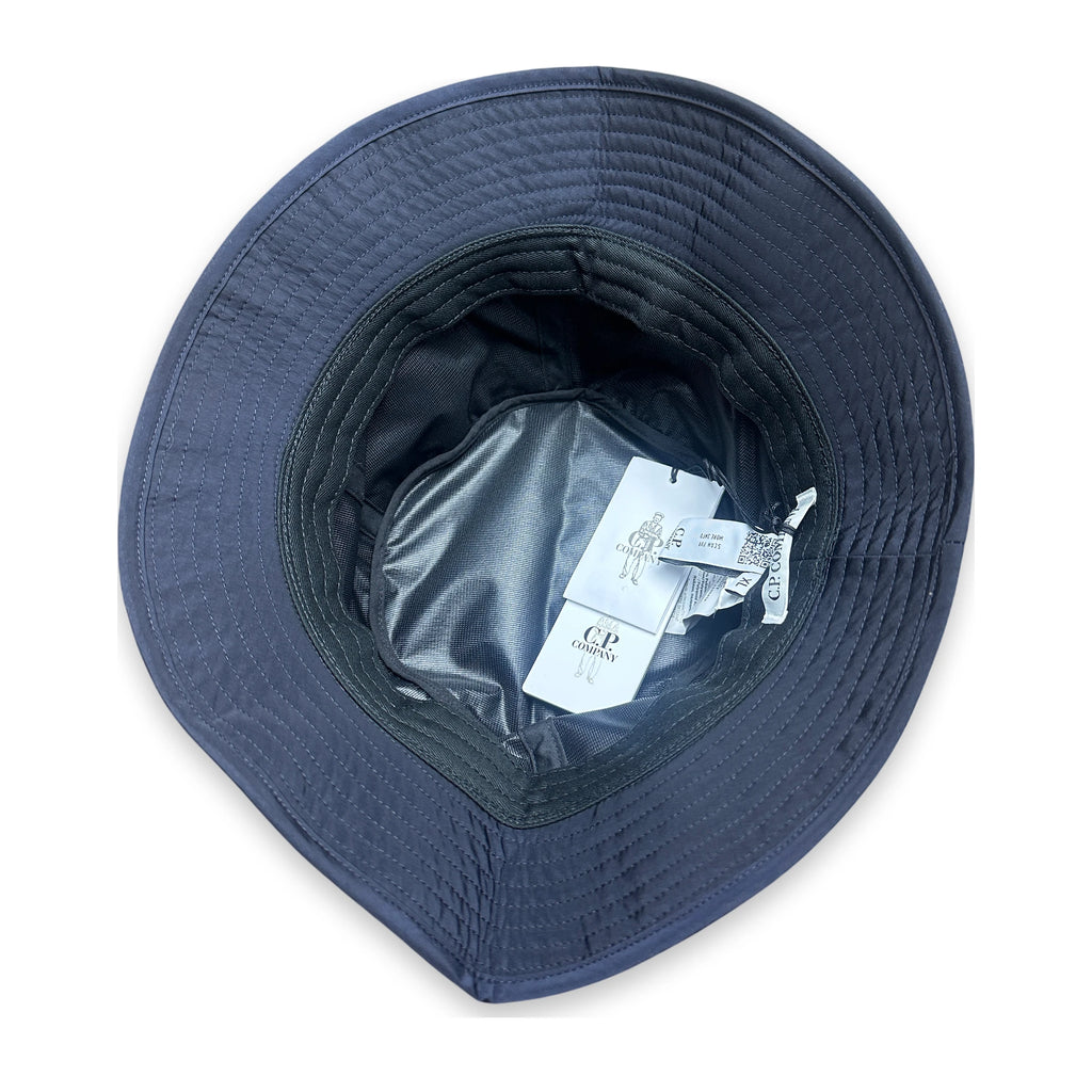 A navy blue wide-brim bucket hat shown from a top-down view, featuring a padded brim, dark interior lining, and attached white product tags.