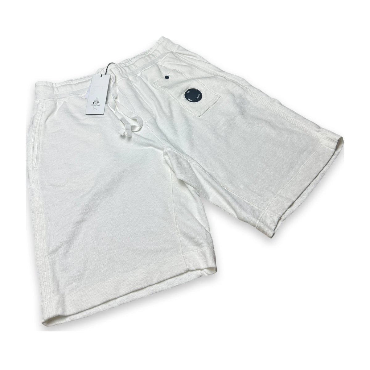 White relaxed sweatpants with a lens of the brand C.P. Company and a swingtag on a white background